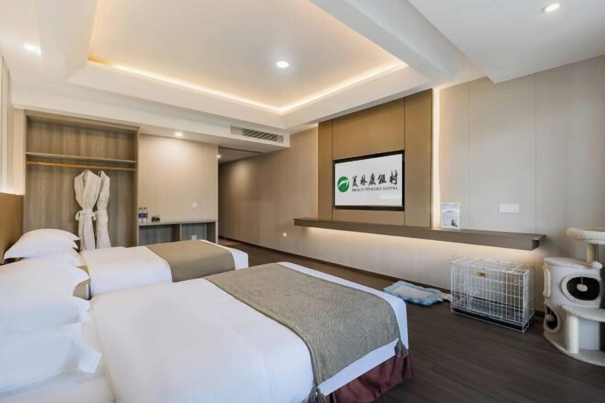 Quarto de hotel com duas camas, uma escrivaninha, um arranhador para gatos e um quadro pendurado na parede.