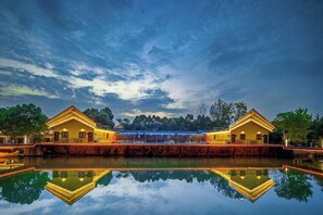 A hotel with a reflective pool in front, two symmetrical buildings with a central walkway, and a clear sky. - Anji Meilin Resort (Anji)