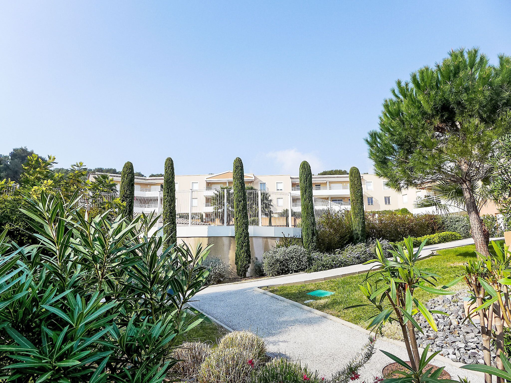 A landscaped garden with a pathway leading to a building with multiple balconies.