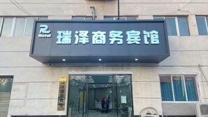 Entrada de un hotel con un letrero que dice "瑞泽商务宾馆" y "Hotel".