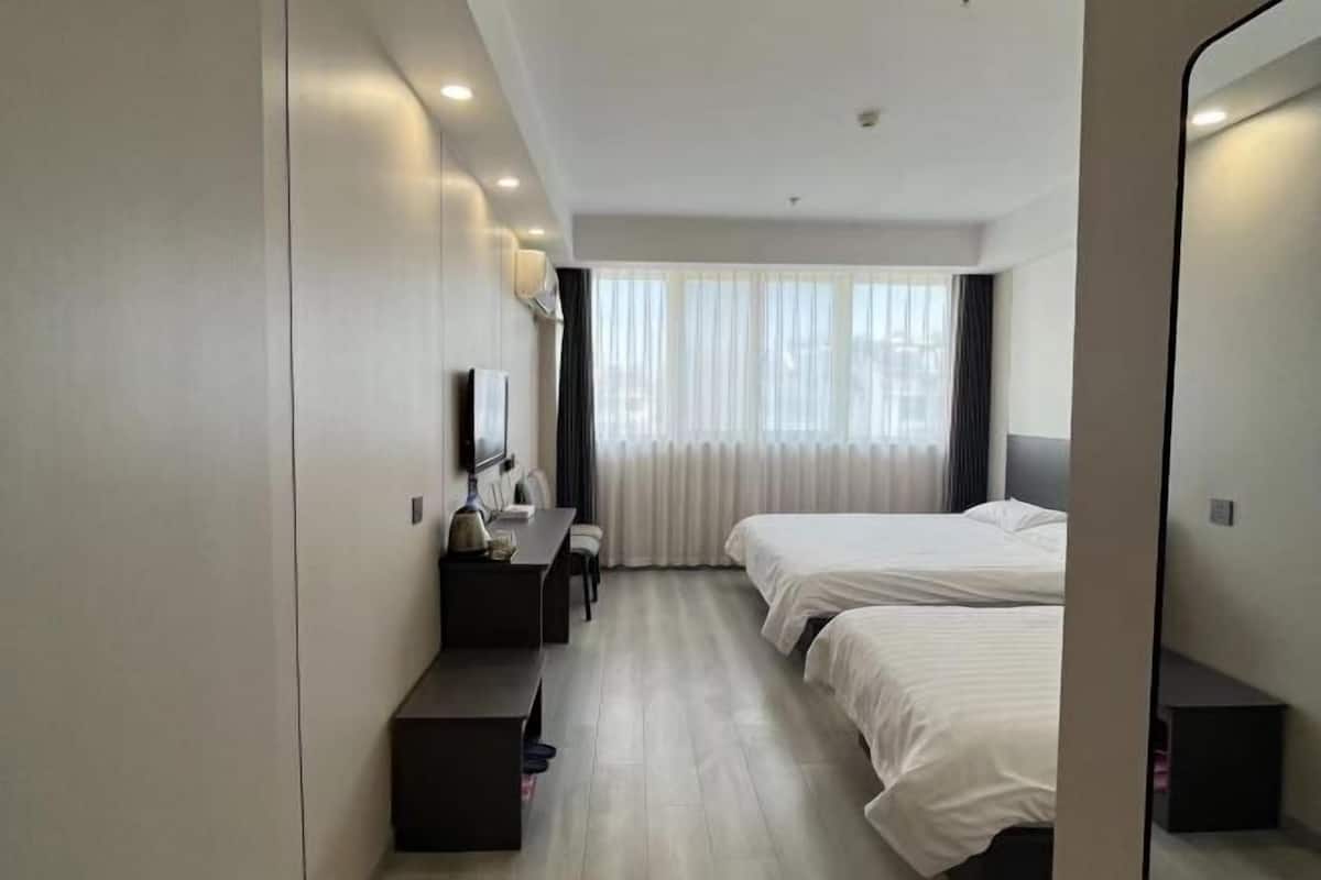 Une chambre d’hôtel avec deux lits, un bureau, une chaise, un téléviseur à écran plat et un grand miroir.