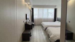 Una habitación de hotel con dos camas, un escritorio, una silla, un televisor de pantalla plana y un espejo grande.