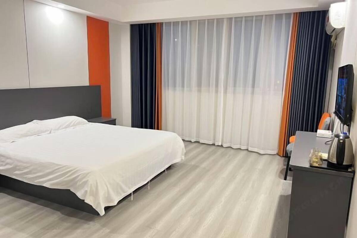 Une chambre d’hôtel avec un lit, un bureau doté d’une lampe et un téléviseur.