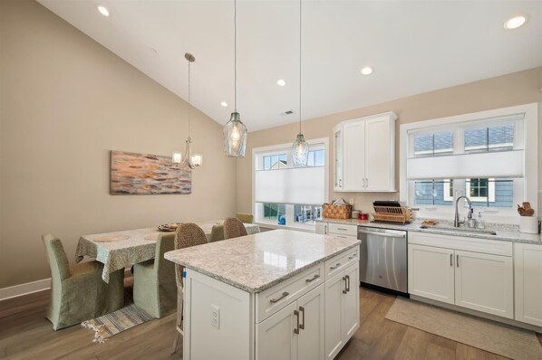 A modern kitchen with white cabinets, a granite countertop, and pendant lighting.