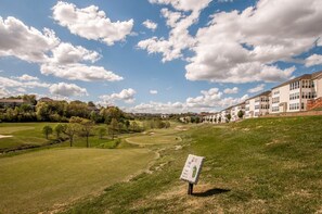 A golf course with a clubhouse and residential buildings in the background.
