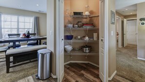 A compact kitchen with built-in shelves, a trash bin, and a dining area with a bench and table.