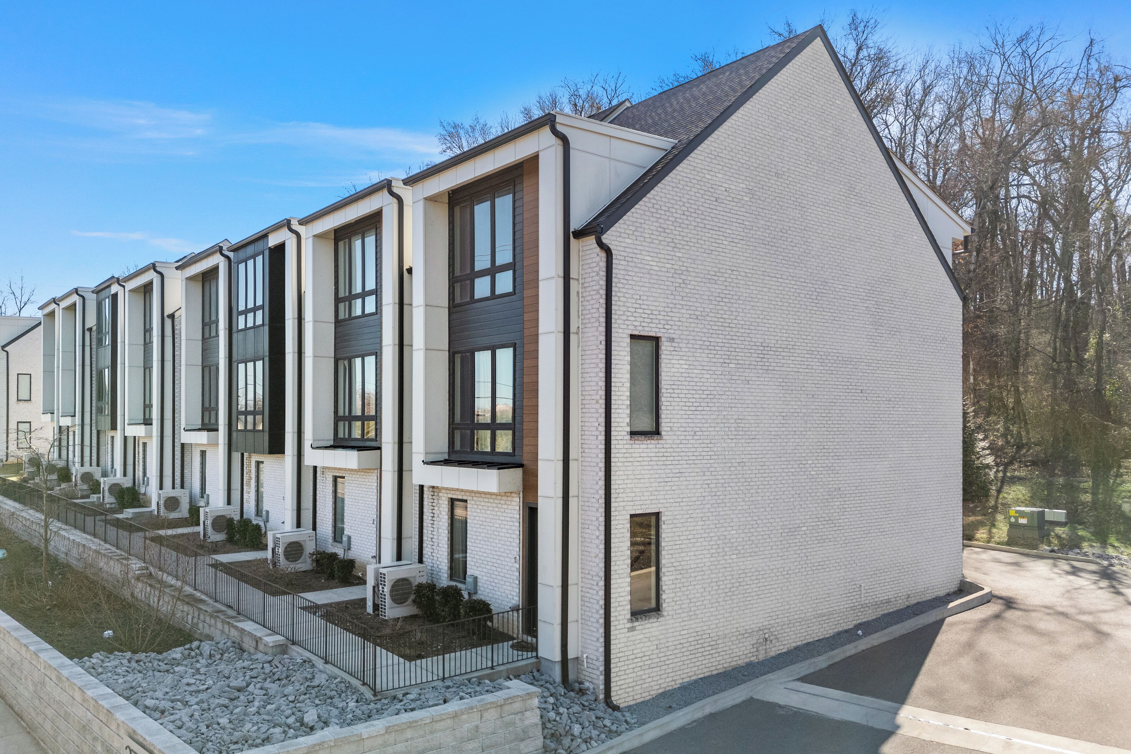A row of modern, white-brick apartment buildings with large windows and air conditioning units.