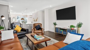 A modern living room with a leather sofa, a coffee table, a black leather chair, and a blue cabinet. - Cozy Haven in Hermitage (Nashville)