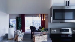 A modern kitchen with a stainless steel oven, a microwave, and a built-in dishwasher. There is a knife block and a woven basket on the counter.