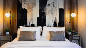 A modern bedroom with a large bed, two nightstands, a wall art piece, and a clock.