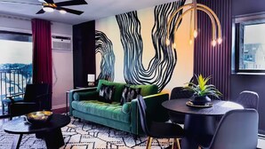 A modern living room with a green sofa, a round table, and a unique wall mural.