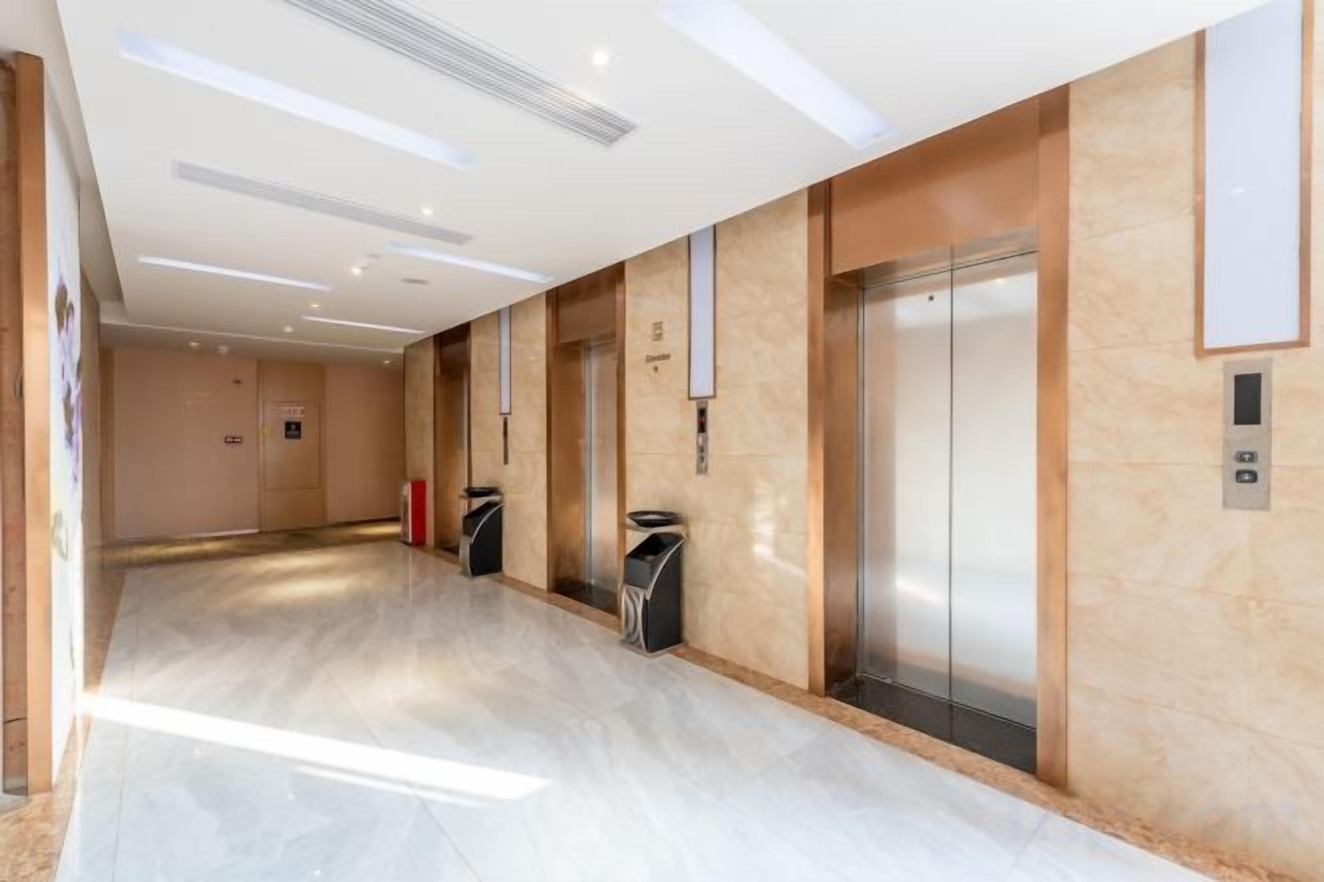 A modern elevator area with a marble floor and a wall-mounted elevator control panel.