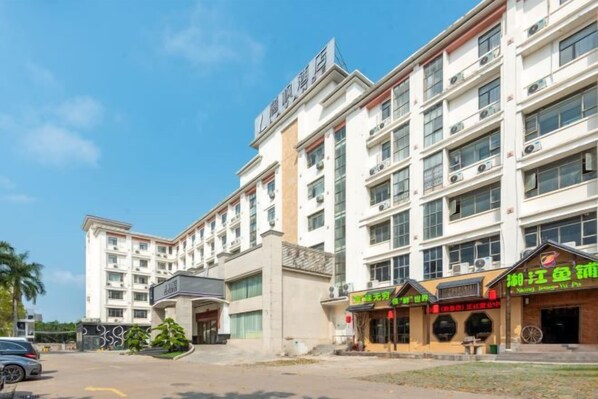 A multi-story hotel with a central entrance, multiple balconies, and a parking area in front. - Xinken Hotel (Guangzhou)