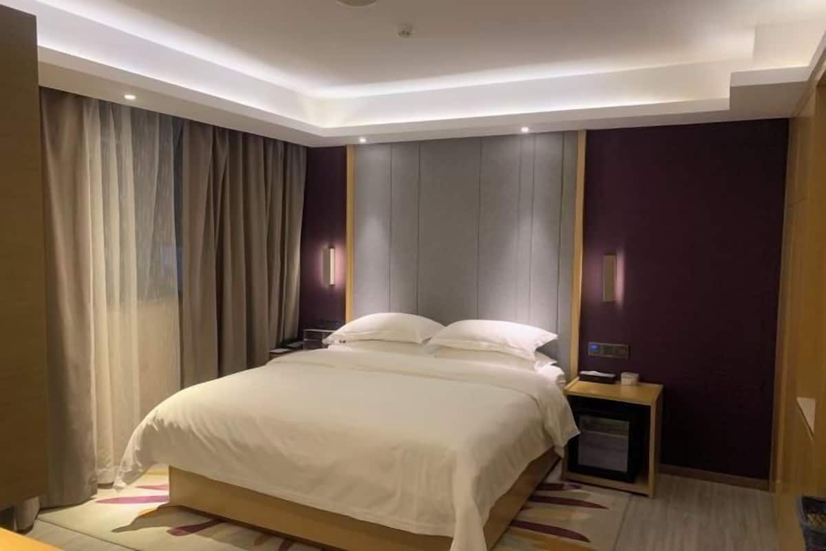 Una habitación de hotel con una cama, una mesita de noche y una lámpara fijada a la pared.