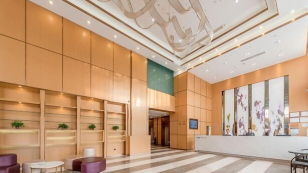 Un hall amplio con mostrador de recepción, zona de estar y una gran pared decorada con obras de arte.