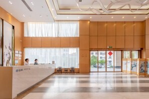 Un vestíbulo amplio con una recepción, ventanas grandes y un diseño moderno y cuidado.