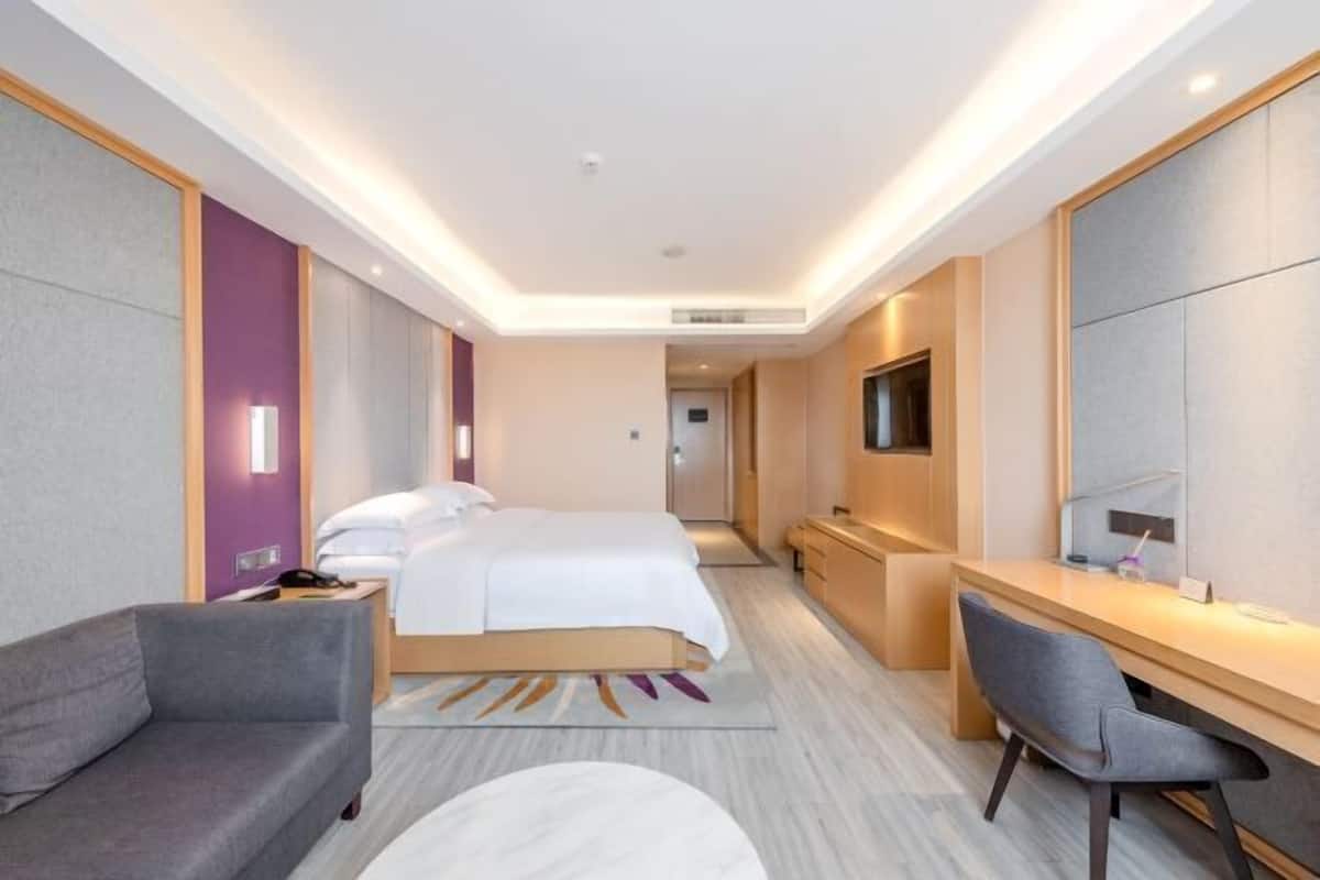 Una habitación de hotel moderna con cama, escritorio, silla y televisión.