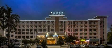 A hotel with multiple floors, a central entrance, and several parking spaces in front.