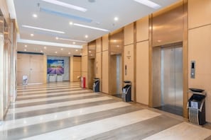 A hotel lobby with a striped floor, elevators, and a reception desk. - Xinken Hotel (Guangzhou)