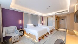 Habitación de hotel con dos camas, un sofá, un escritorio y un televisor.