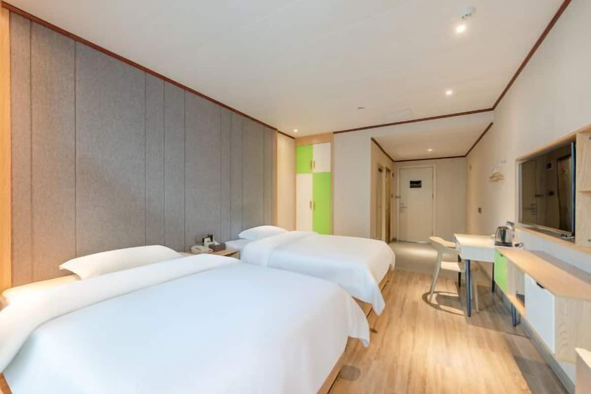 Habitación de hotel con dos camas, un escritorio, un espejo y baño.