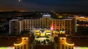 Un gran hotel con un patio central, varios pisos y señalización iluminada.