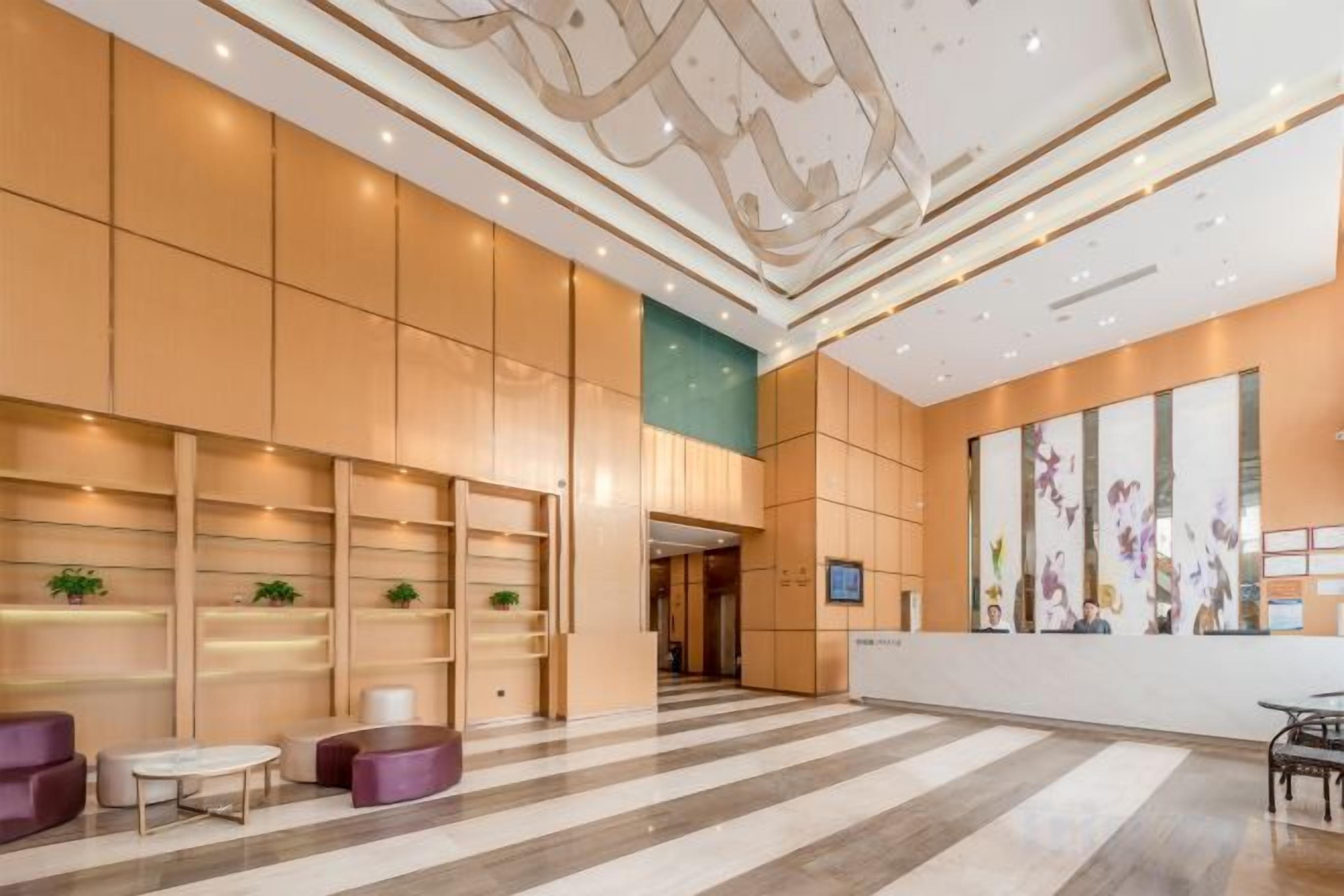 A hotel lobby with a reception desk, seating area, and decorative wall art.
