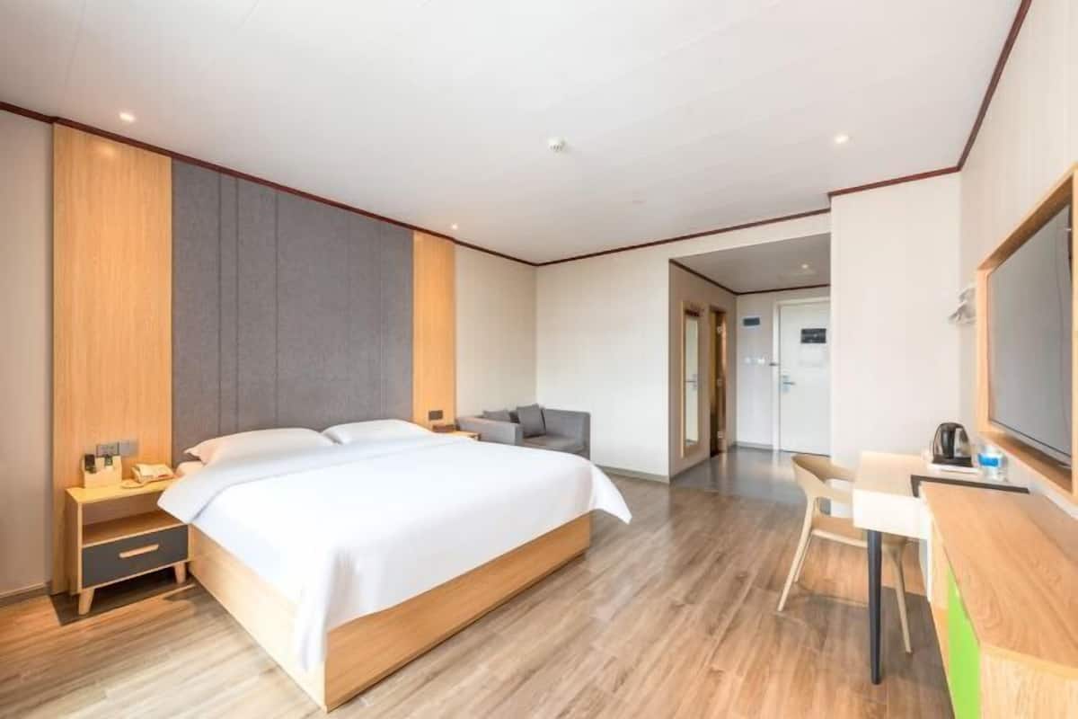 Una habitación de hotel moderna con una cama grande, un escritorio, una silla y un televisor.