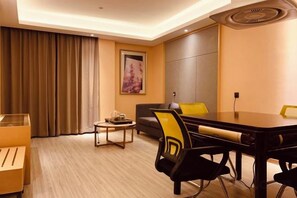 A hotel room with a dining table, chairs, a sofa, a coffee table, and a painting on the wall. - Xinken Hotel (Guangzhou)