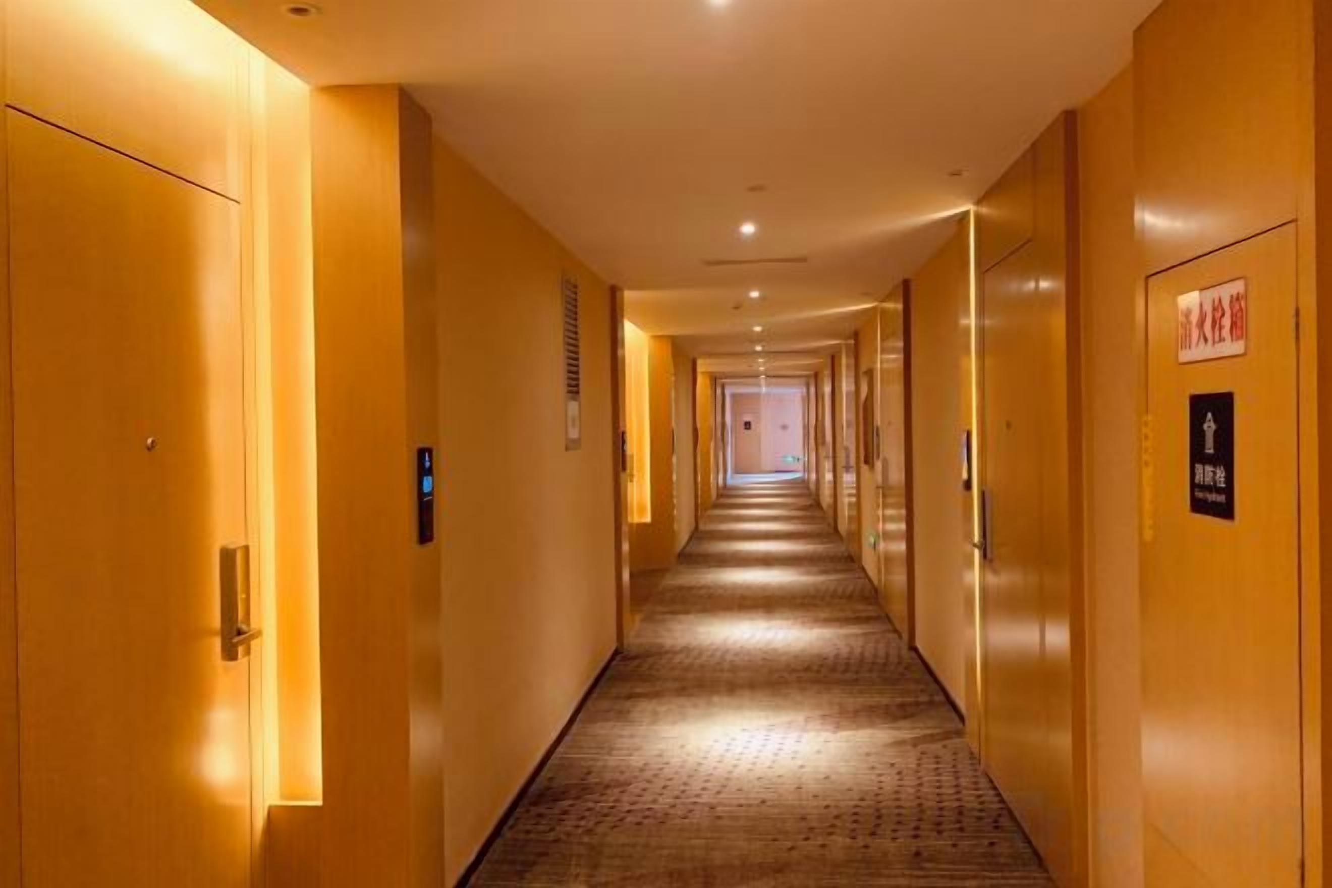 A hotel corridor with doors on both sides, a carpeted floor, and a sign indicating a smoking area.