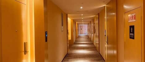 A hotel corridor with doors on both sides, a carpeted floor, and a sign indicating a smoking area.