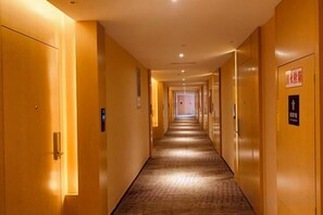 Ein Hotelgang mit Türen auf beiden Seiten, einem Teppichboden und einem Schild, das auf einen Raucherbereich hinweist.