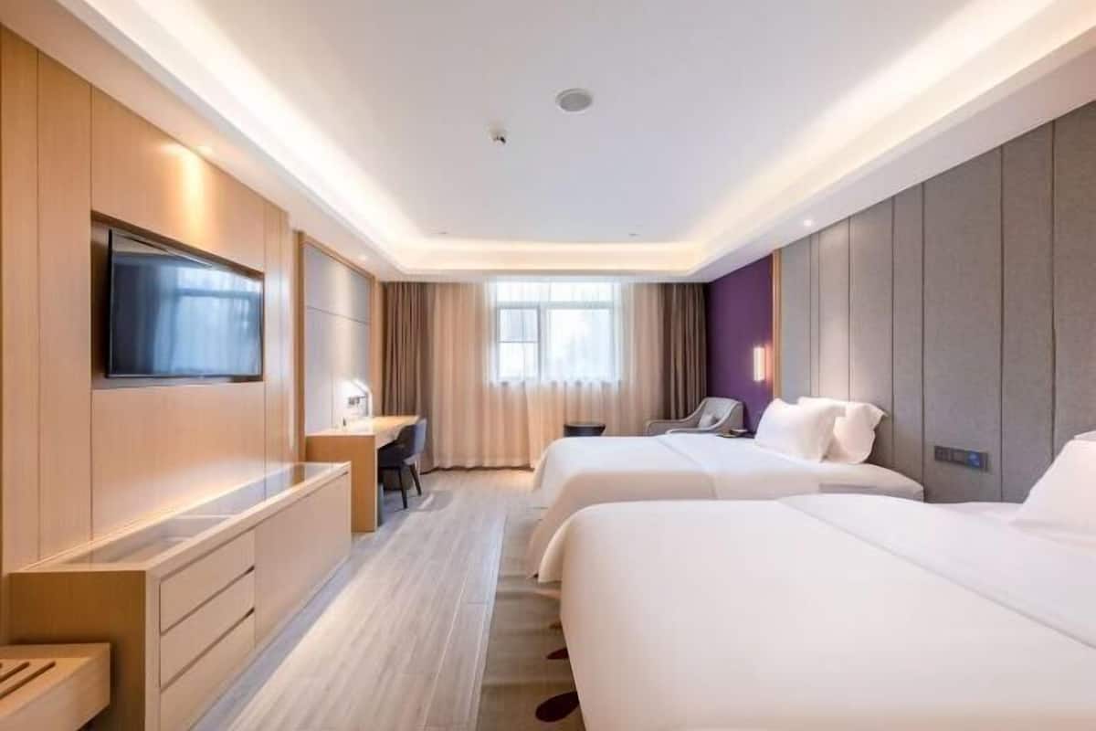Habitación de hotel con dos camas, un escritorio, un televisor y una ventana con cortinas.