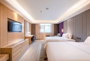 Habitación de hotel con dos camas, un escritorio, un televisor y una ventana con cortinas.