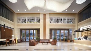 A spacious lobby with a high ceiling, a coffee bar, seating area, and large windows. - Neijiang International Hotel (Wanda E-commerce Center) (Neijiang)