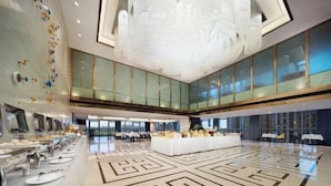 A spacious hotel lobby with a central seating area, a buffet with multiple food stations, and large windows offering a view of the cityscape. - Neijiang International Hotel (Wanda E-commerce Center) (Neijiang)