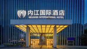 The entrance of the Neijing International Hotel with a modern glass facade and a covered entrance area. - Neijiang International Hotel (Wanda E-commerce Center) (Neijiang)
