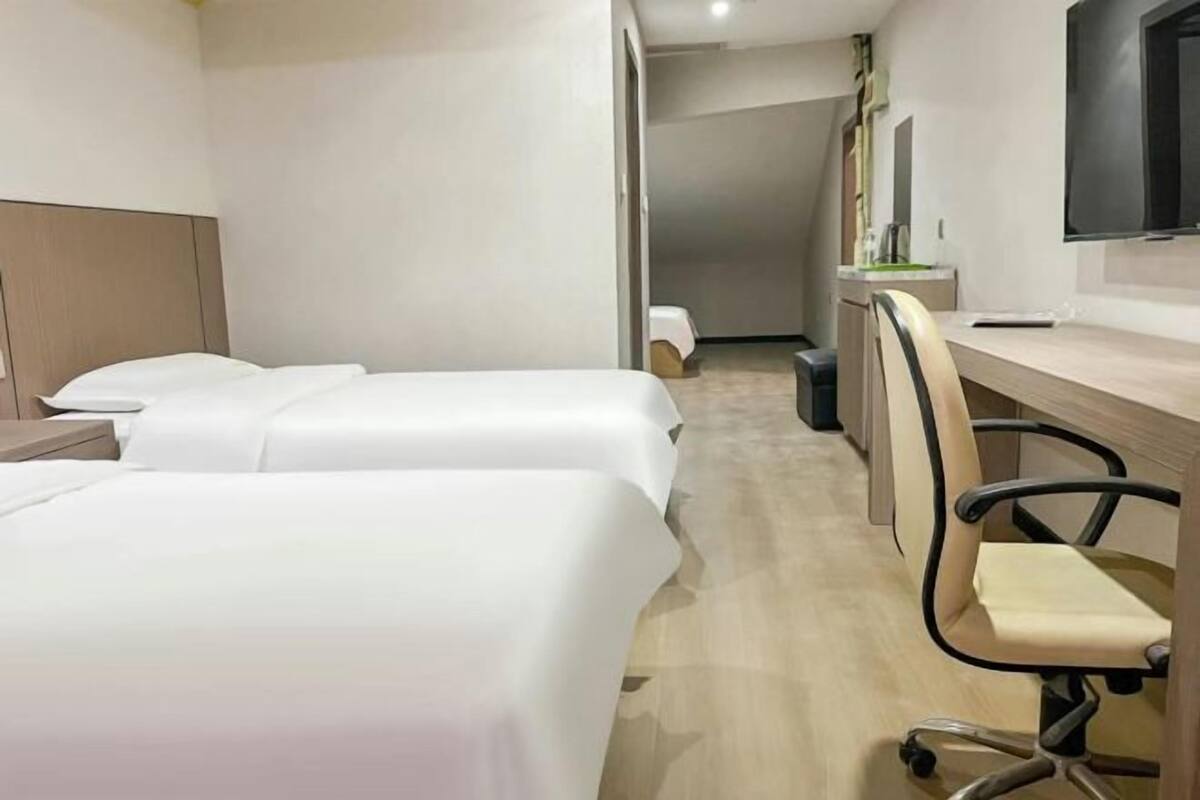 Ein Hotelzimmer mit zwei Betten, einem Schreibtisch und einem Stuhl.