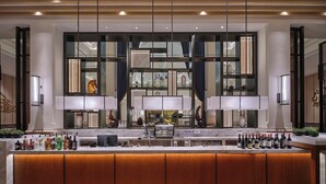 A modern bar area with a long counter, multiple bottles of alcohol, and a large window with a view of the interior. - Yingde Chocolate Kingdom Hotel (Qingyuan)