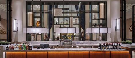 A modern bar area with a long counter, multiple bottles of alcohol, and a large window with a view of the interior.