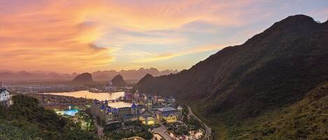 A resort with a central building surrounded by lush greenery and hills.
