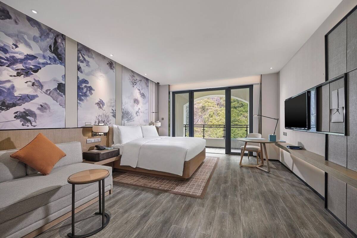 Un dormitorio moderno con una cama grande, un sofá, un escritorio y un televisor.