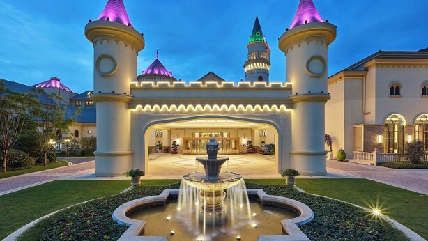 A castle-like hotel entrance with a fountain, two towers, and a well-maintained garden. - Yingde Chocolate Kingdom Hotel (Qingyuan)