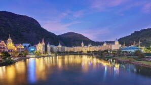 A hotel with multiple buildings, a large body of water in the foreground, and mountains in the background. - Yingde Chocolate Kingdom Hotel (Qingyuan)
