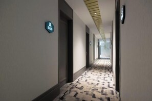A hotel hallway with a patterned carpet and doors marked with room numbers.