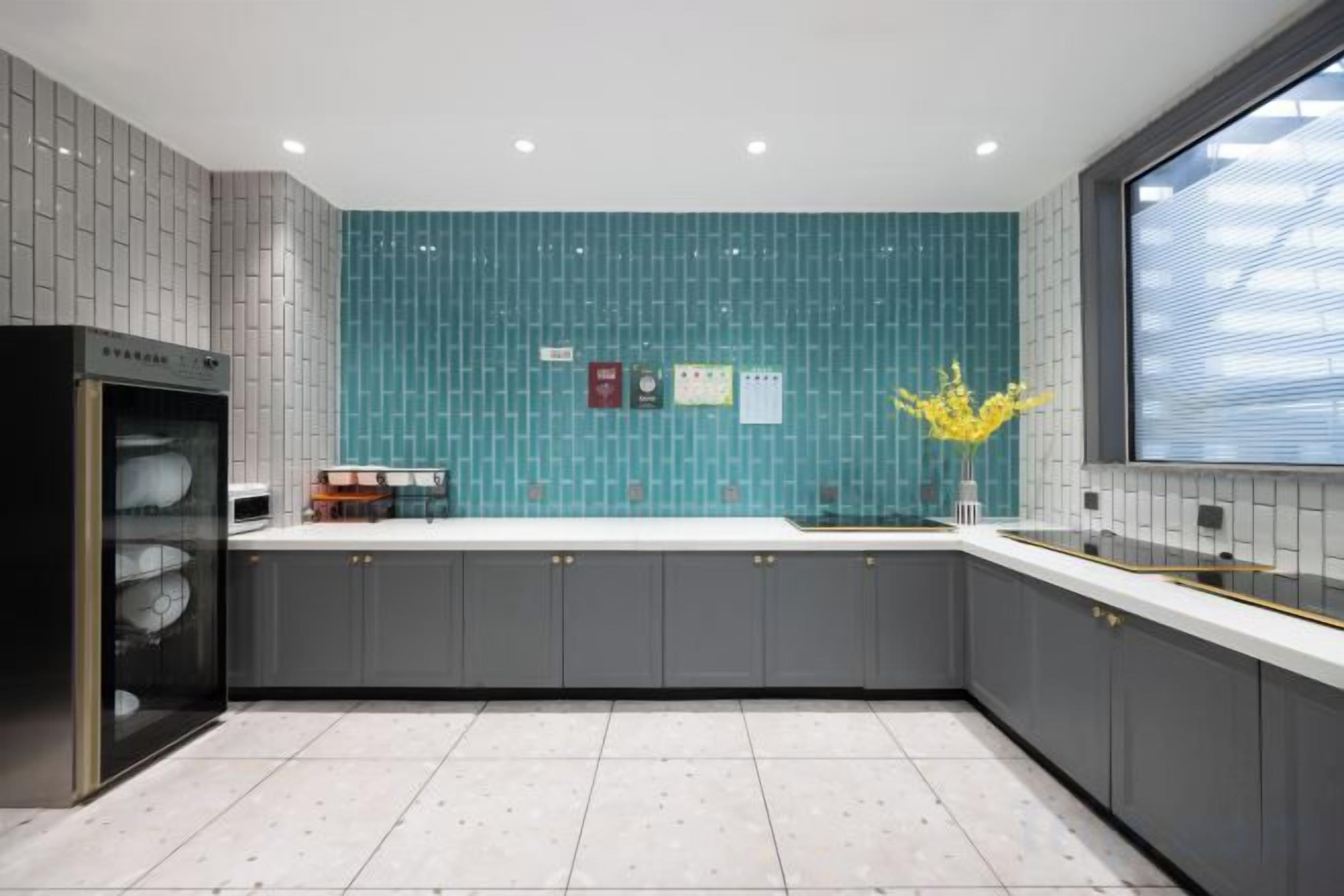 Una cocina moderna con gabinetes grises, encimera blanca y salpicadero verde azulado.