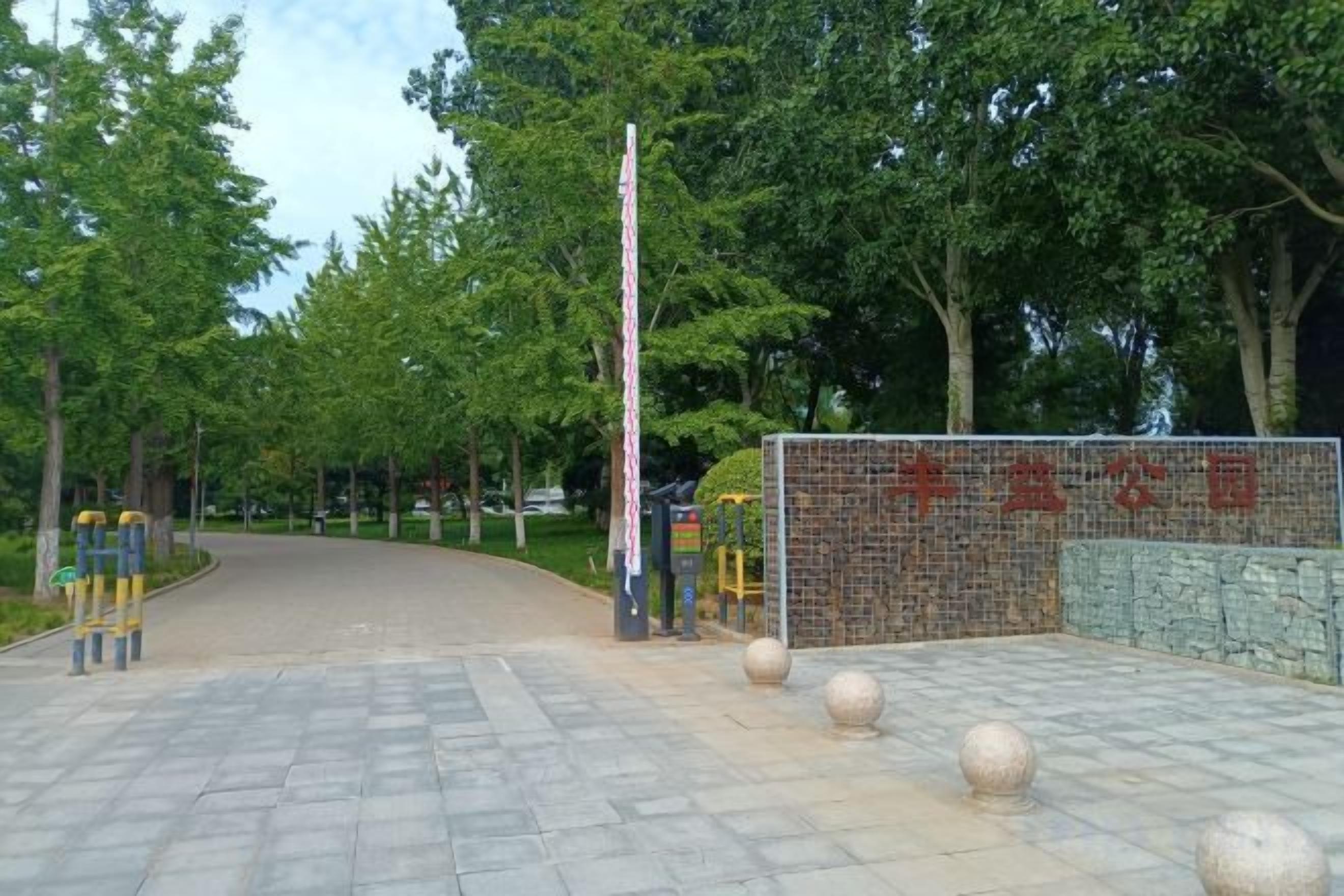 Una entrada pavimentada con un muro de piedra y una puerta metálica.