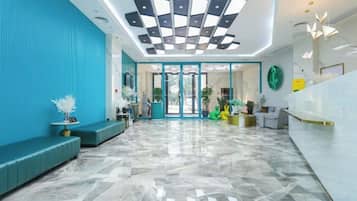 Um hall de hotel com balcão de recepção, área de estar e piso estampado.