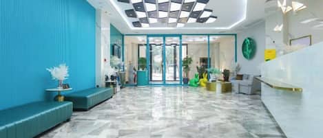 A hotel lobby with a reception desk, seating area, and a patterned floor.
