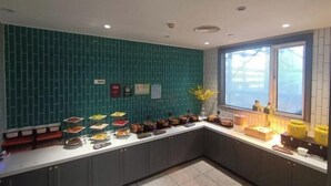 Una cocina moderna con salpicadero color turquesa, diversos alimentos en la encimera y una ventana con persianas.